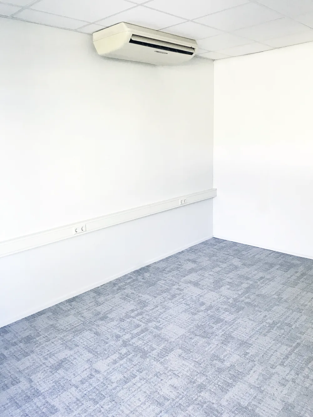 Lege kantoorruimte met witte wanden en airconditioning aan het plafond